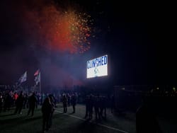 A video board displaying "CLINCHED" in front of a large contingent of STLFC Supporters on the pitch with fireworks in the background.